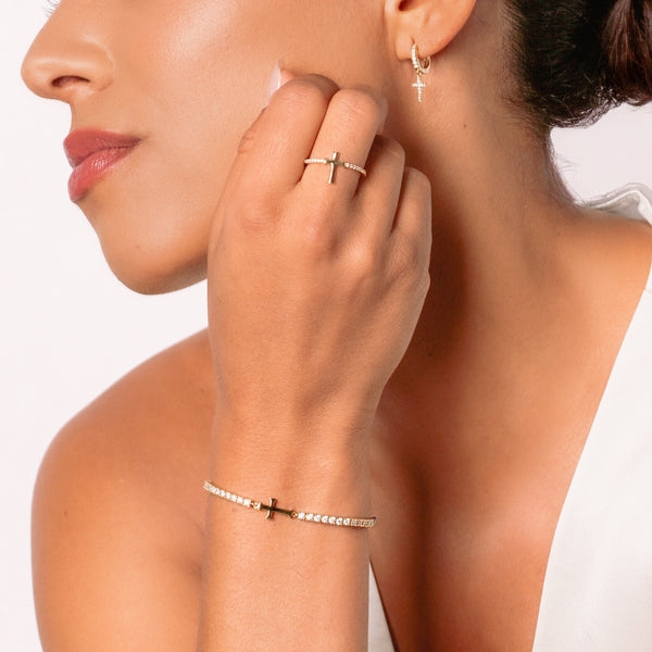 Close-up of a christian women's jewelry model wearing the Luminous Cross Pave ring with the matching Cross Tennis Bracelet and Hoop Earrings from the Calvary Collection by Rizen Jewelry.