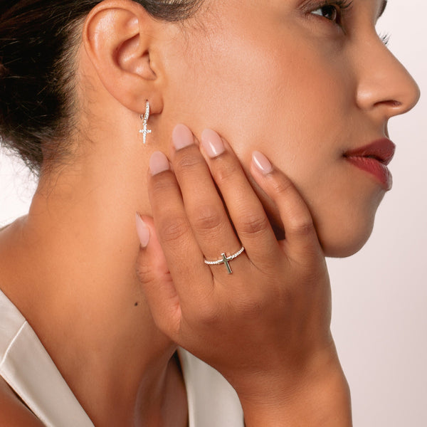 Close-up of a christian woman jewelry model wearing the silver luminous cross earrings and luminous cross pave ring from the Calvary Collection by Rizen Jewelry.