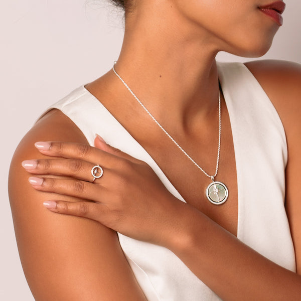 Close-up of a christian woman wearing a sterling silver adoring star compass ring and True Direction Compass Necklace from Rizen Jewelry's Insignia Collection.