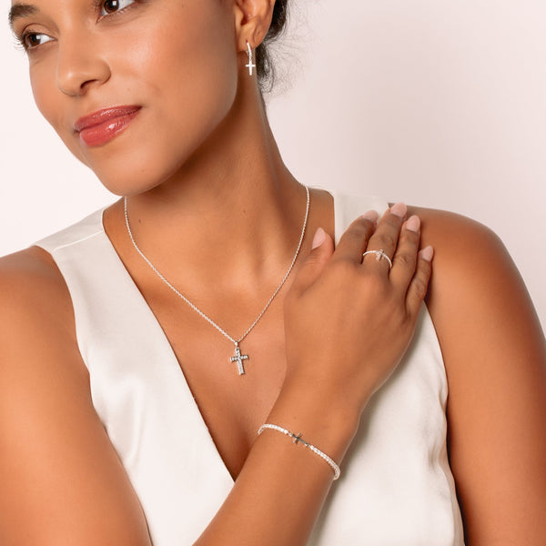 A christian woman jewelry model wearing the silver luminous cross jewelry from the Calvary Collection by Rizen Jewelry.
