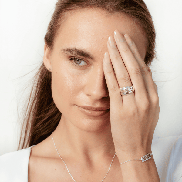 Christian woman wearing the sterling silver Olive Branch Ring, Bracelet and mini cross earrings from the Rooted Collection by Rizen Jewelry. 